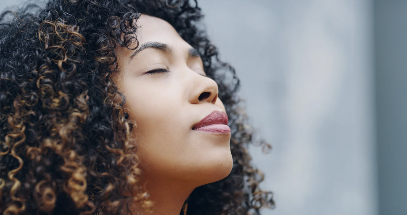 Close-up of a woman with curly hair and closed eyes.